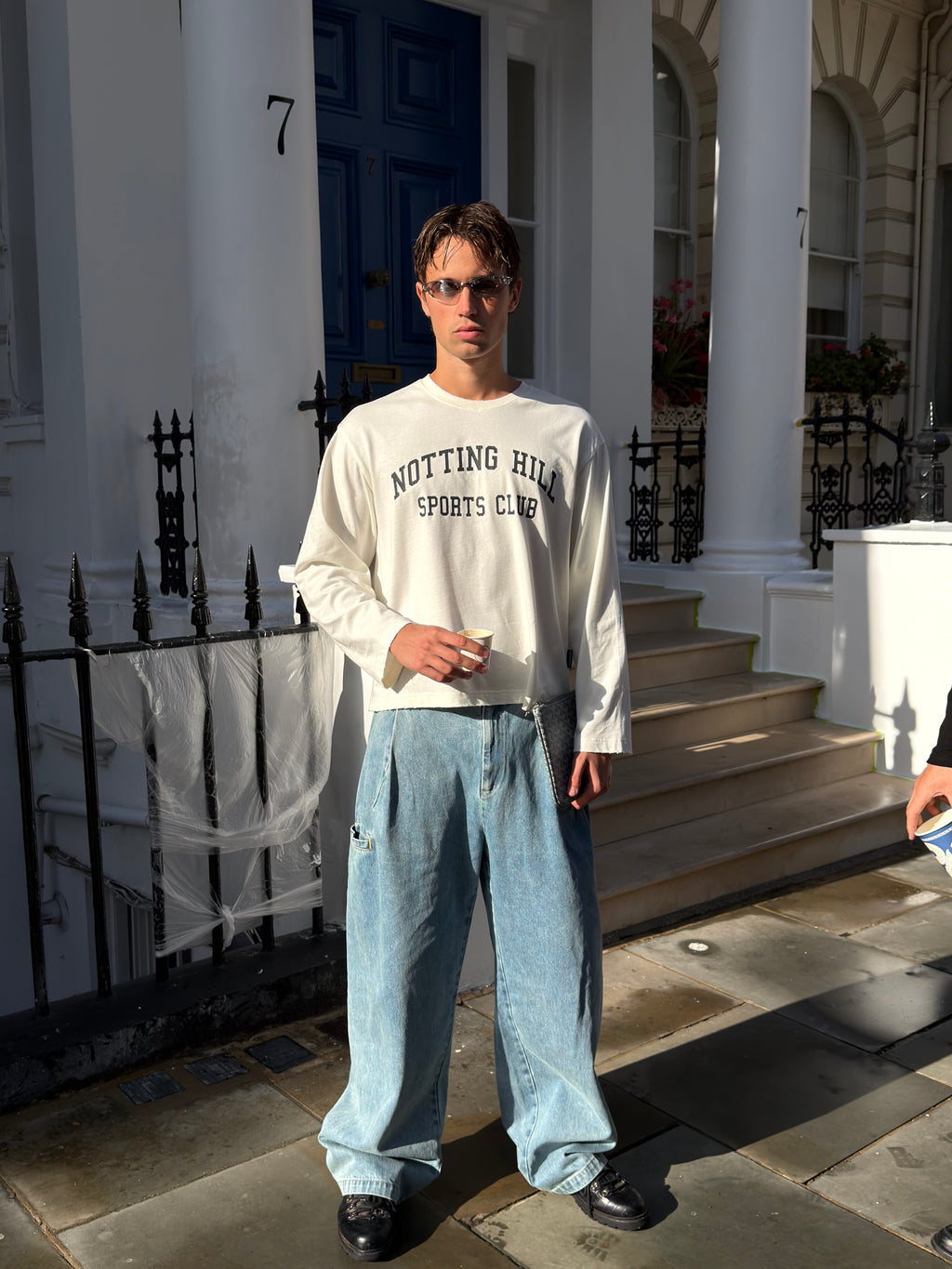 White Notting Hill Sports Club long-sleeve tee, full-length, worn by a model outside a townhouse