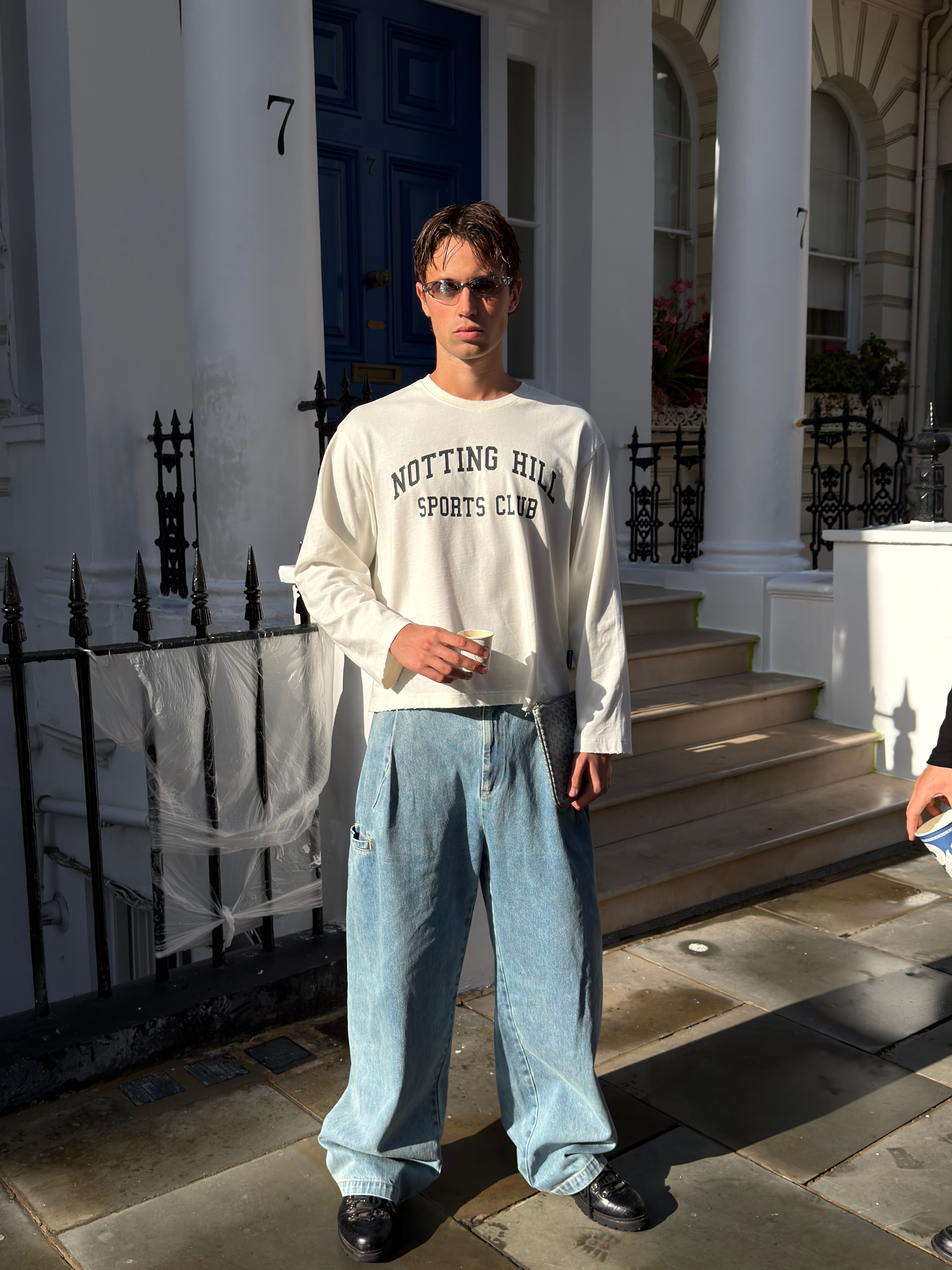 White Notting Hill Sports Club long-sleeve tee, full-length, worn by a model outside a townhouse